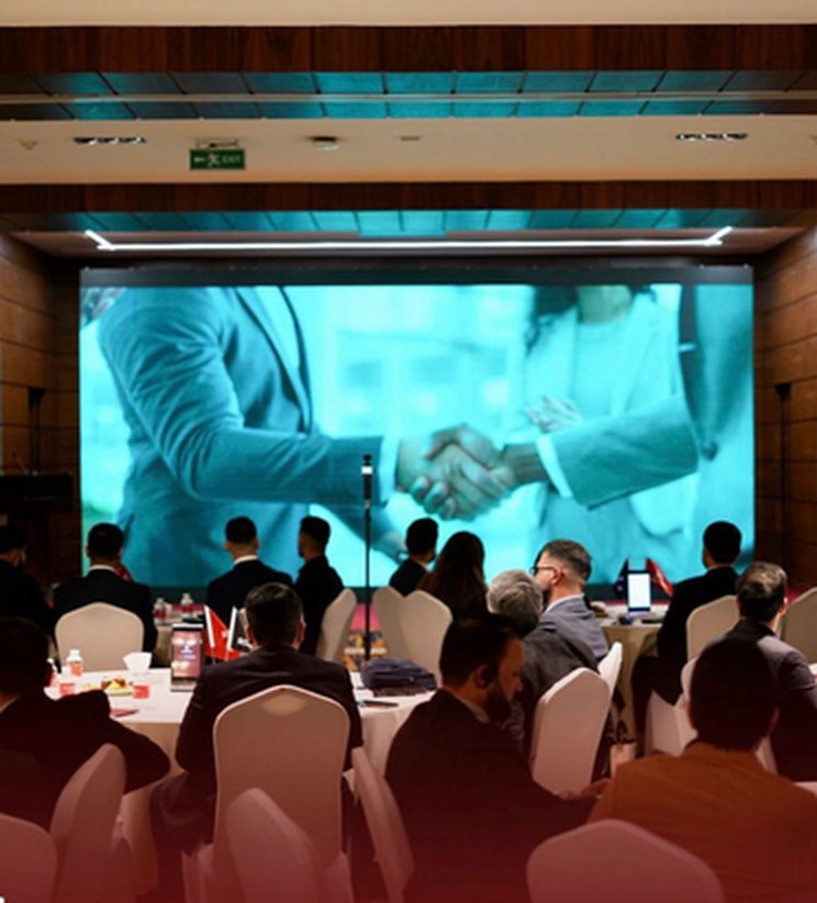 A 1001 Businessmen gathering with members seated before a large stage screen